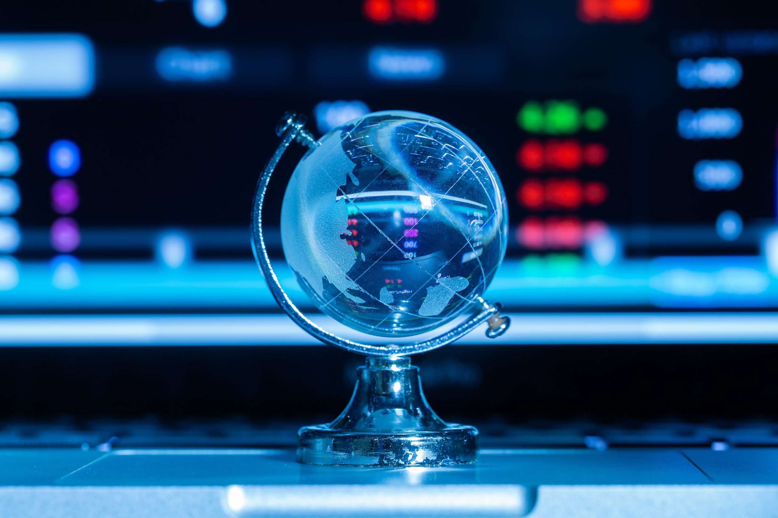 Crystal globe with stock information on the computer screen and dark blue background