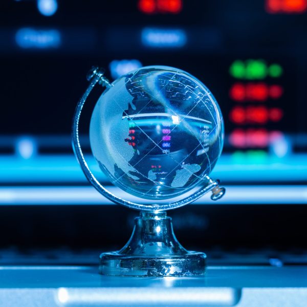 Crystal globe with stock information on the computer screen and dark blue background