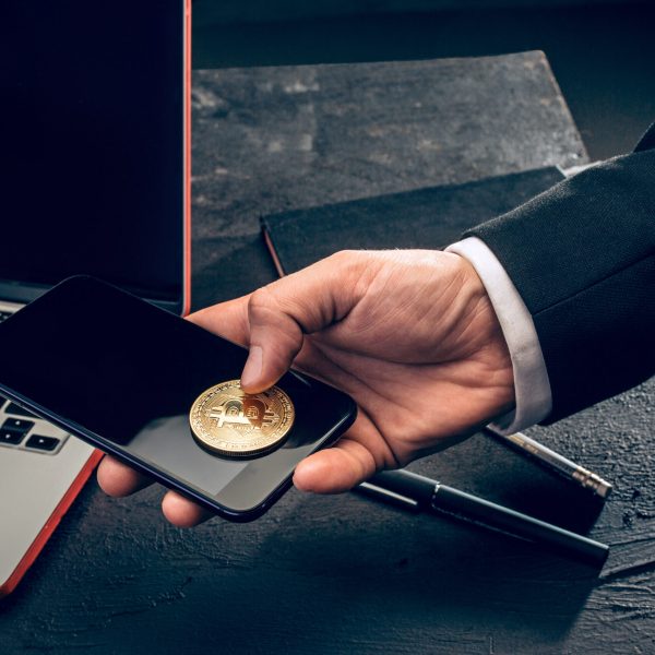 The golden bitcoin and mobile phone in male hands. Cryptocurrency bitcoin coins. Litecoin, Bitcoin, Ethereum, e-commerce, busibess, finance concept. crypto currency symbol. virtual electronic money concepts